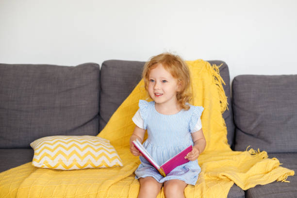 istock 3-year-old girl sits at home on the couch with a pink glittery notebook 1496626564