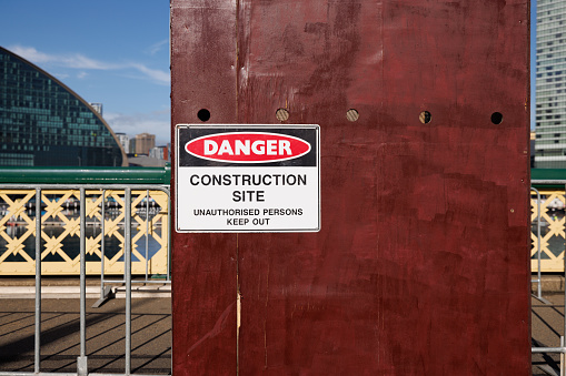Danger, construction site sign on a brown wall.