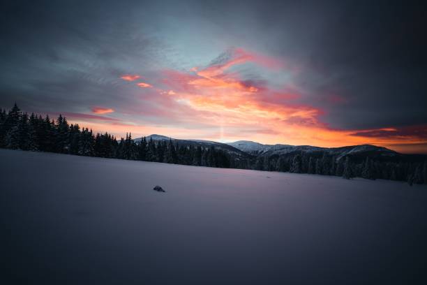 istock Tranquil winter scene with a snow-covered mountain slope and a forest in the background at sunset 1496627221