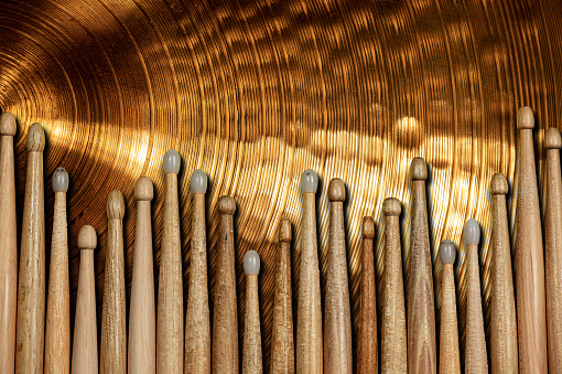 Close-up of a large group of wooden drumsticks on a golden colored cymbal with copy space. Percussion instrument.