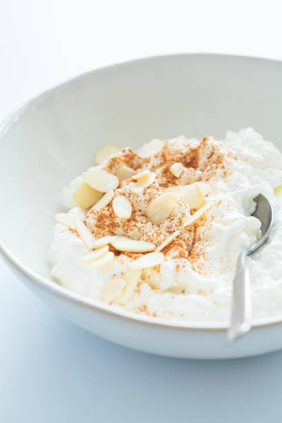 istock Cottage cheese with cinnamon and almonds in white bowl, white background. Healthy protein breakfast concept. 1496636922