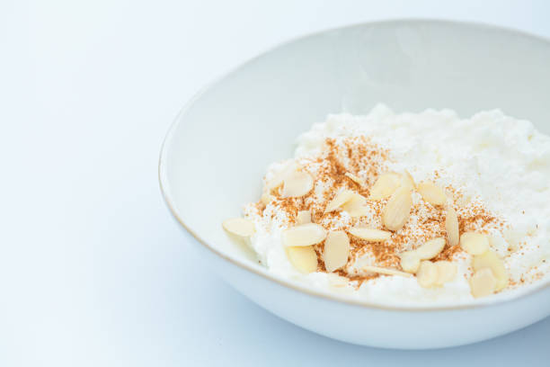 istock Cottage cheese with cinnamon and almonds in white bowl, white background. Healthy protein breakfast concept. 1496636969