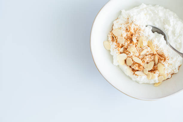 istock Cottage cheese with cinnamon and almonds in white bowl, white background. Healthy protein breakfast concept. 1496637010