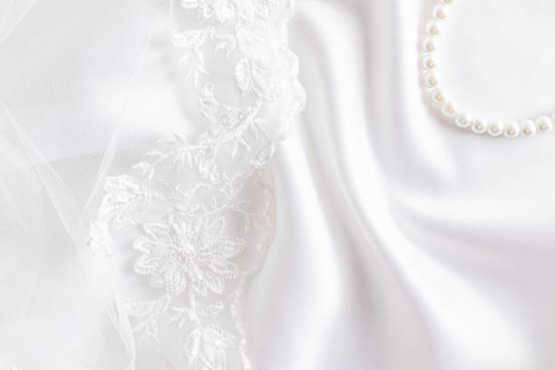 White lace bridal veil on a satin background with soft waves, pearl beads. Layout for cover design, postcard, photo album