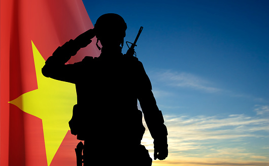 Silhouette of a saluting soldier against the Vietnam flag and blue sky. EPS10 vector