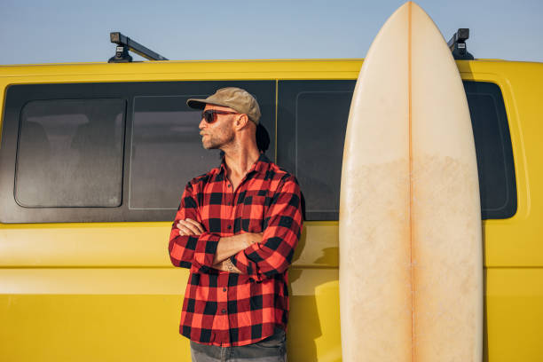 istock Portrait of a man with surfing board next to a van 1496639984