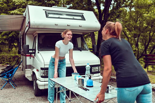 Smiling Females Utilizing Teamwork To Carry Around Table While Camping With RV
