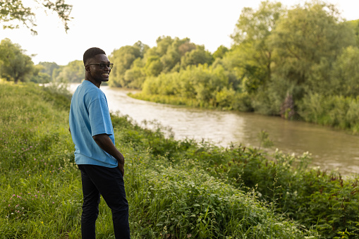 Young African man enjoying the nature around him near a river