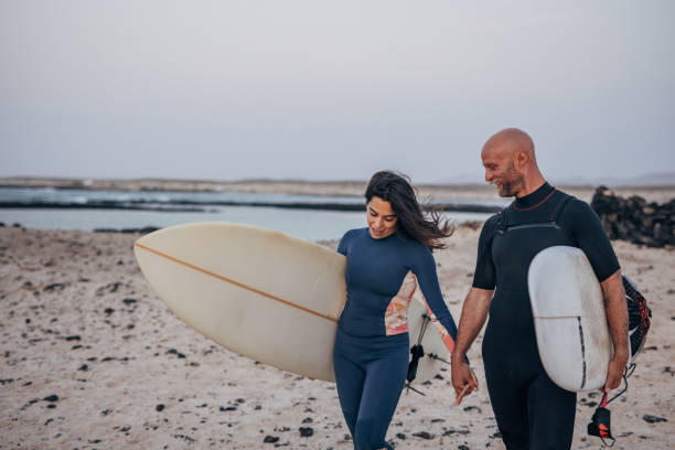 istock Couple in love going surfing on the beach 1496648625