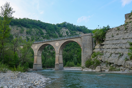 arches of old aqueduct over the river Enza in Neviano degli Arduini, Parma, Emilia Romagna, Italy across the mountains and sky