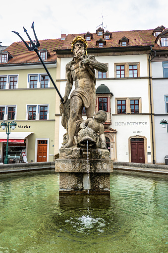 Weimar, Germany - May 10, 2023: Neptune fountain from 1774 by Martin Gottlieb Klauer with gold crown and trident on marketplace square in Weimar, Germany