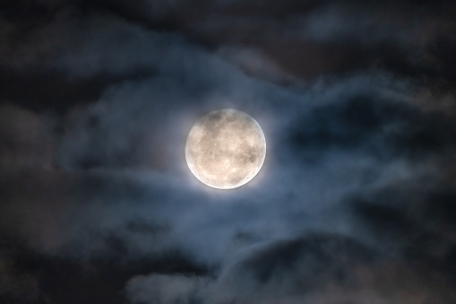 The third large full moon of 2023, shows up in the clouds, and looks mysterious.
