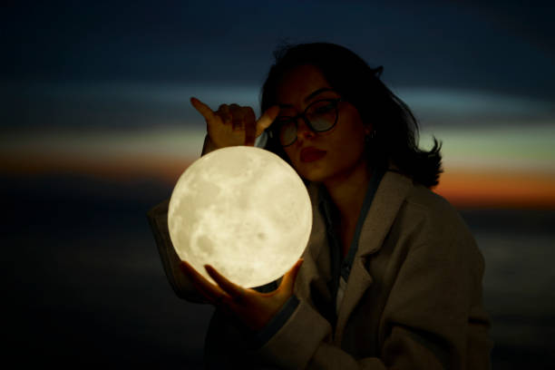 istock young lady playing with a moon shaped artificial lamp outdoors 1496649486