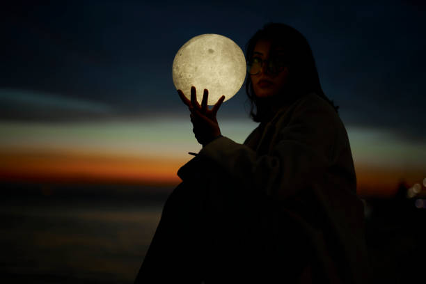 istock young lady playing with a moon shaped artificial lamp outdoors 1496649685