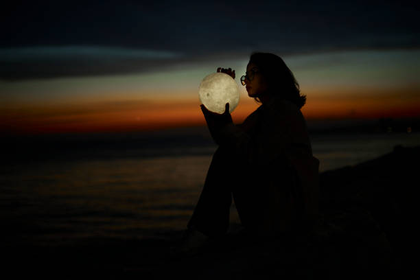 istock young lady playing with a moon shaped artificial lamp outdoors 1496649837