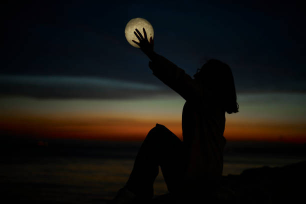 istock young lady playing with a moon shaped artificial lamp outdoors 1496649852