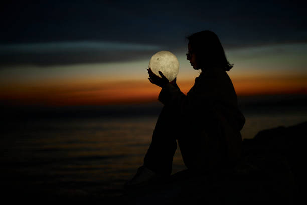 istock young lady playing with a moon shaped artificial lamp outdoors 1496649873