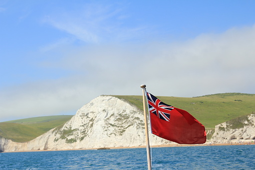 White cliffs and Durdle Door with the Red Ensign flag flying in the foreground. Jurassic coast, Dorset, South coast of England