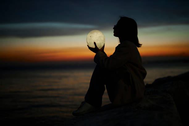 istock young lady playing with a moon shaped artificial lamp outdoors 1496650058