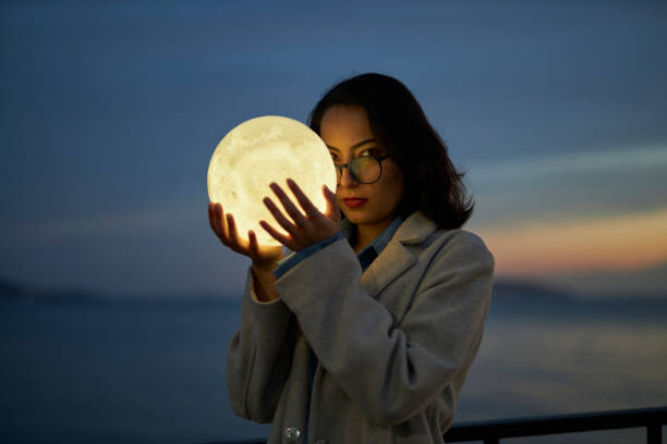 istock young lady playing with a moon shaped artificial lamp outdoors 1496650121