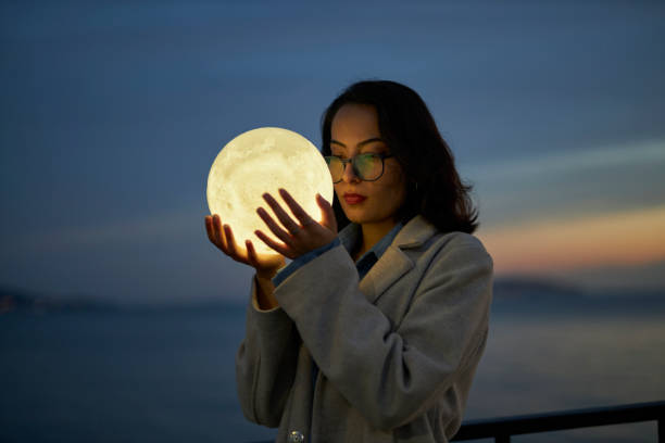 istock young lady playing with a moon shaped artificial lamp outdoors 1496650310