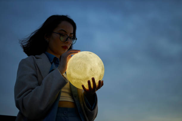 istock young lady playing with a moon shaped artificial lamp outdoors 1496650314