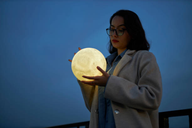 istock young lady playing with a moon shaped artificial lamp outdoors 1496650316