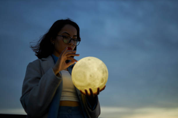 istock young lady playing with a moon shaped artificial lamp outdoors 1496650323