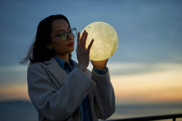 istock young lady playing with a moon shaped artificial lamp outdoors 1496650376