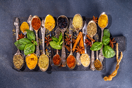 Spices for cooking on dark background . Different seasonings, spices and herbs paprika, pepper, turmeric, salt, basil, mint, cinnamon, garlic, olive oil, aromatic ingredients for preparation food
