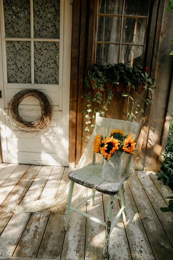 A fresh bouquet of sunflowers set on a cozy, rustic porch.