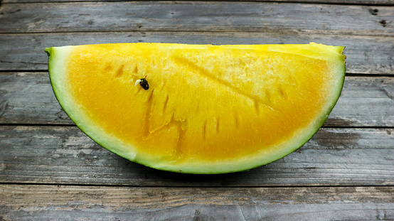 Yellow watermelon slices on wooden plate and isolated on gray board background. Healthy food, vegan. Antioxidant