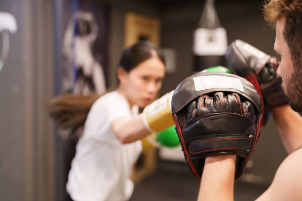 istock Female boxer punching  exercises with trainer 1496666614