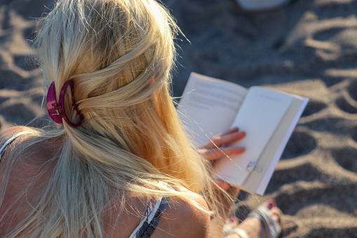 Close-up of a woman reading book on the beach