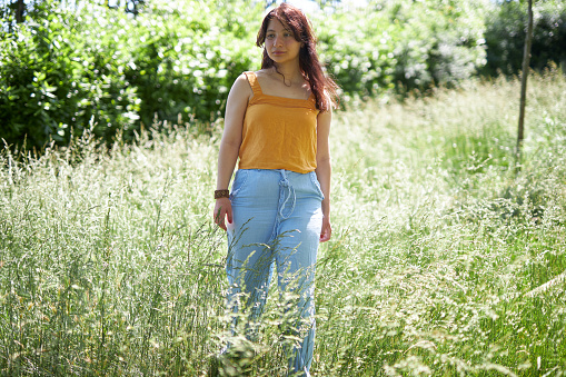 girl in blue jeans and orange shirt walking around forest