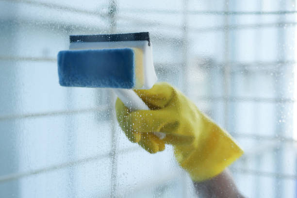 istock hand in gloves cleaning window glass with a brush 1496670179