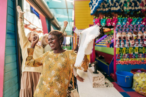 Senior woman group dancing in an amusement park and having fun together. Looks like they are just won a new game