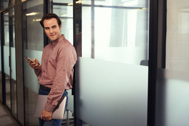 istock Guy with laptop and smartphone standing in empty office corridor 1496678120