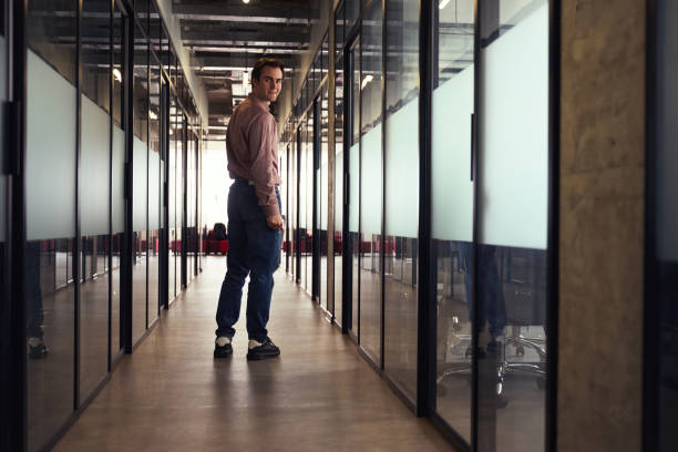 istock Pleased corporate worker smiling at someone in office corridor 1496678255