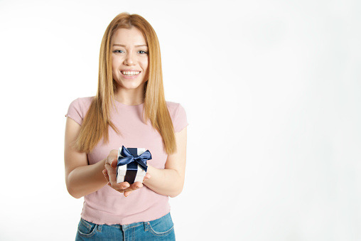 Caucasian female is holding gift box in hand.