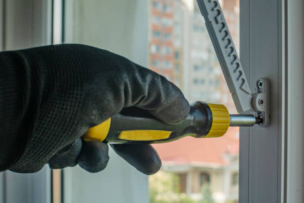 istock Close-up of a man's hand in a construction glove tightens a screw that fixes a plastic window opening limiter. Installing a window stopper on a plastic window frame. Installation of window fittings 1496684963