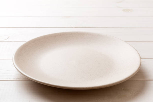 istock Perspective view of empty light plate on wooden background. Empty space for your design 1496685491