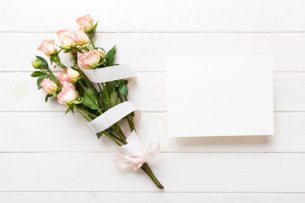 istock Greeting holiday card mockup with fresh roses on colored table background, mock up with copy space for design 1496686128