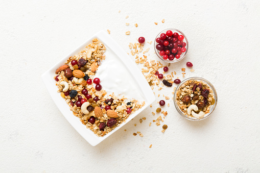 Healthy breakfast food with granola, yogurt, fruits and nuts. Dessert parfait with dried fruits for breakfast.