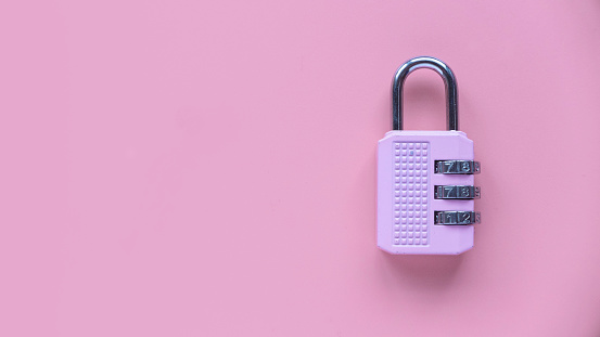 Safety and protection concept. Pink padlock isolated on a pink background with copy space.