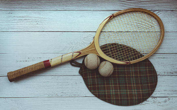 A vintage tennis racket with balls on wood background.