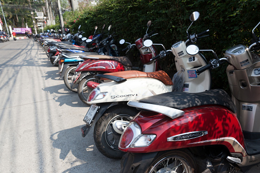 CHIANG MAI, THAILAND - FEBRUARY 21, 2018: A typical street in Chiang Mai, Thailand. Many scooters are parked on the street.
