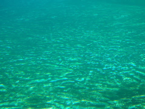 Deep blue sea surface seen from under water, underwater abstract fractal waves and rays of sunlight shine through.