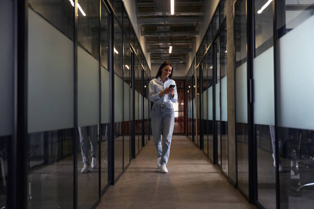 istock Cheerful female using her mobile phone in office hallway 1496700829