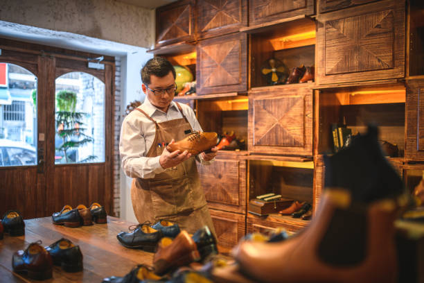 istock Asian Male Shoemaker Observing A Classic Shoe Design In A Small Store 1496702598